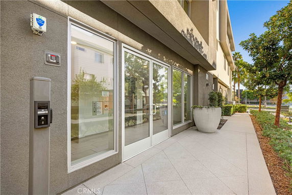 Front view of a building entrance with glass doors and security system.