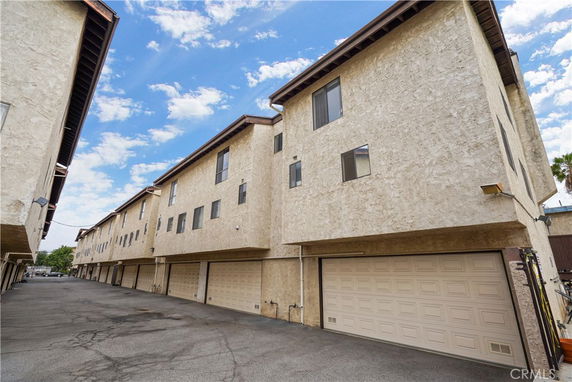 Front view of a multi-story building with garage spaces.