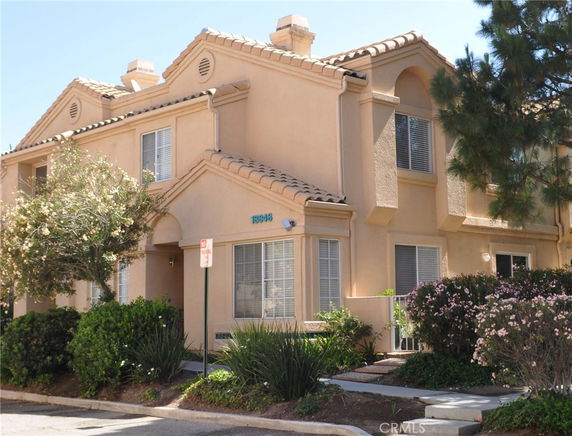 Front view of a two-story townhouse with a tiled roof and beige exterior.