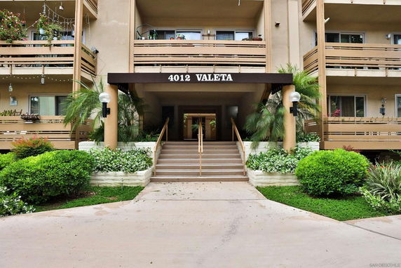 Front view of a multi-story building with balconies and entrance stairs.