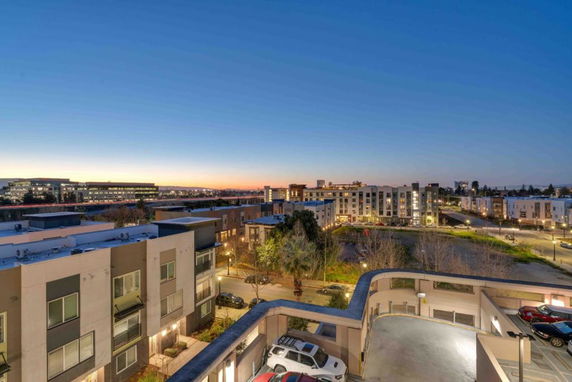Panoramic view of a residential area at dusk, showing multiple buildings and a parking area.
