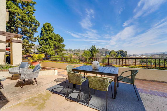 Outdoor patio area with furniture offering a scenic view of trees and distant hills.