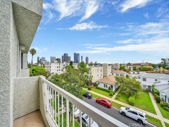Panoramic view from a building balcony showing city skyline and residential neighborhood.