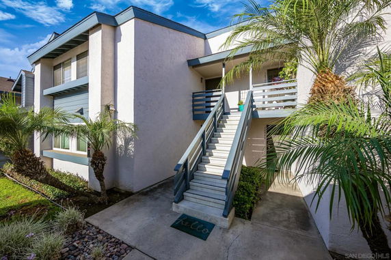 Front view of a multi-story building with an exterior staircase leading to an entrance.