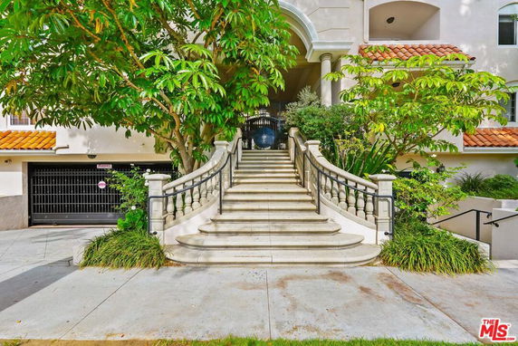 Front view of a building with a staircase and arched entrance.