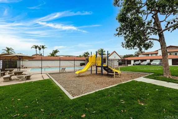 Playground with a slide and climbing structure near a swimming pool.