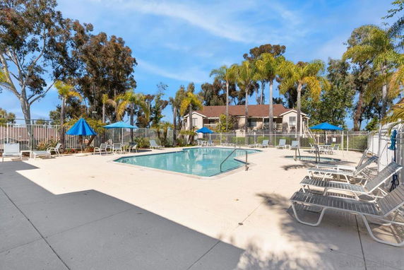 Outdoor swimming pool area with lounge chairs and umbrellas.