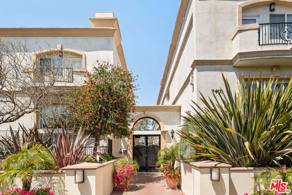 Front view of a multi-story building with a gate and landscaping.