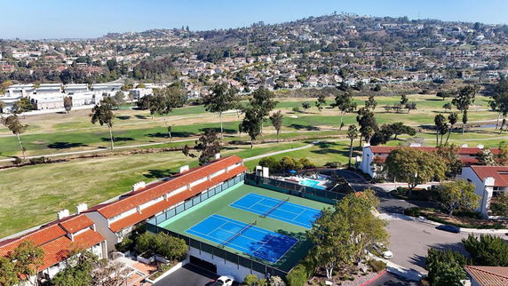 Aerial view of tennis courts and surrounding residential area.