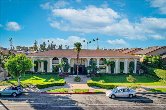 Front view of a two-story building with arched windows and a red-tiled roof.