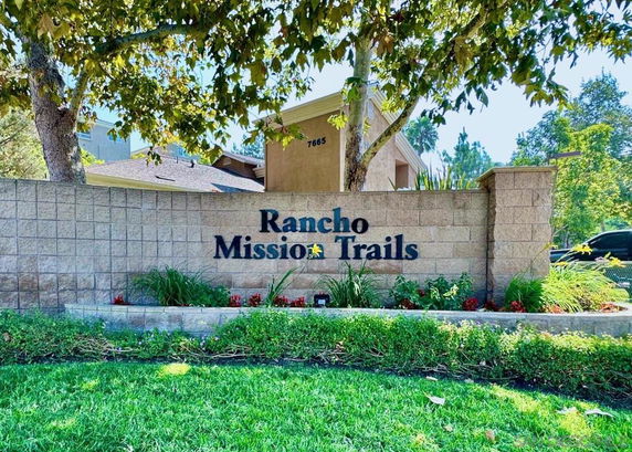Entrance to a residential complex with a brick wall and sign reading 'Rancho Mission Trails.'