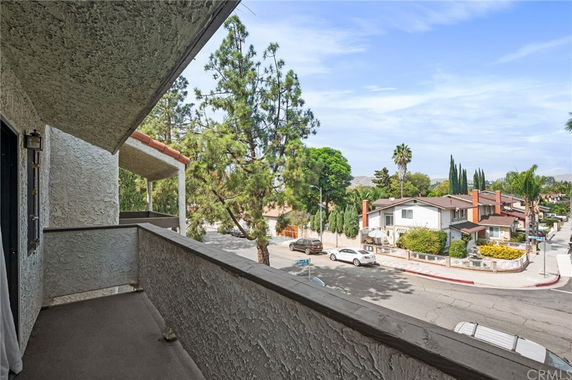 View from a balcony overlooking a suburban neighborhood with houses and trees.