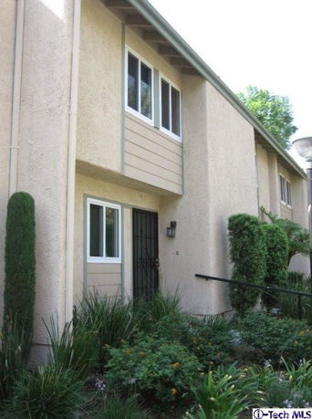 Front view of a two-story house with beige exterior and multiple windows.