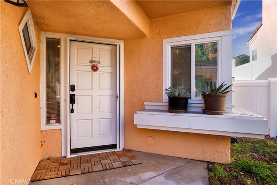 Front view of a house entrance with a white door and small window adjacent to it.