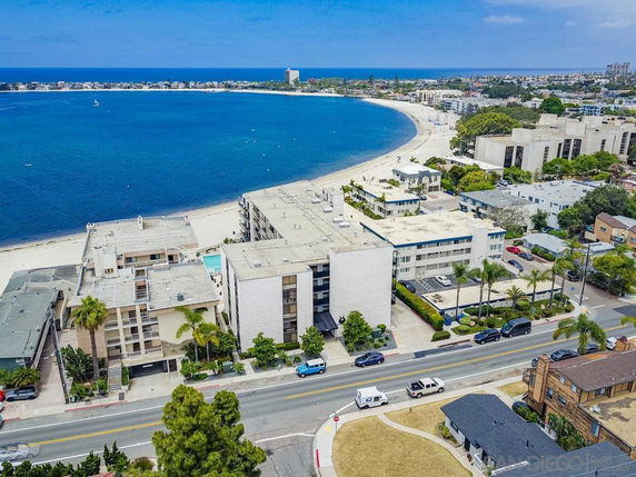 Aerial view of beachfront residential area with buildings and a curved coastline.