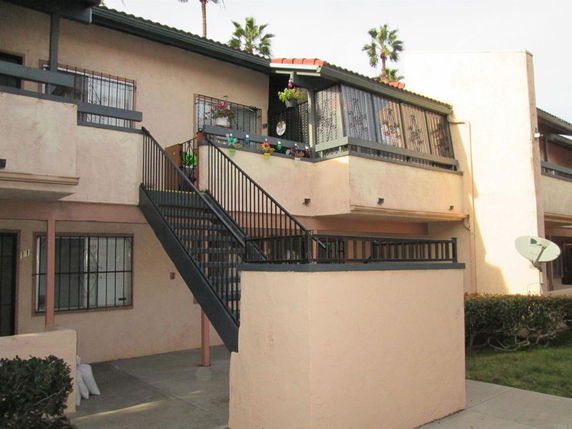 Front view of a two-story apartment building with external staircase and balcony.