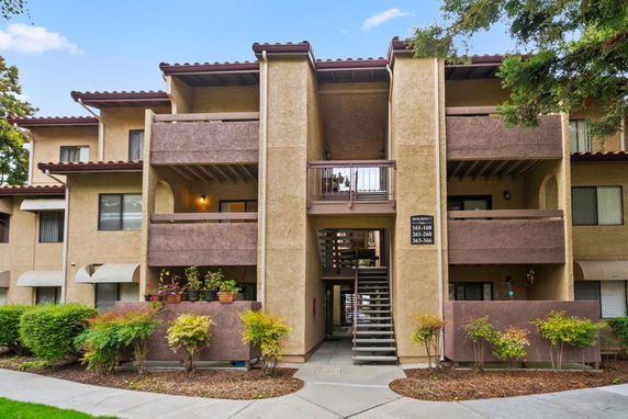 Front view of a multi-story apartment building with balconies and central stairway.
