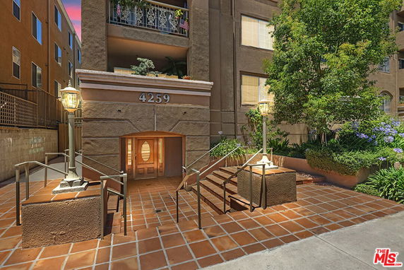 Front view of a multi-story building entrance with steps and railings.
