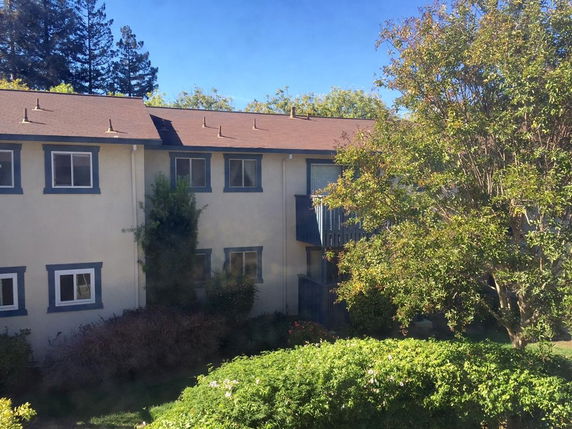 View of a two-story residential building with a sloped roof and multiple windows.
