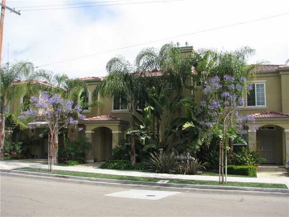 Front view of a two-story house with a tiled roof and lush greenery.