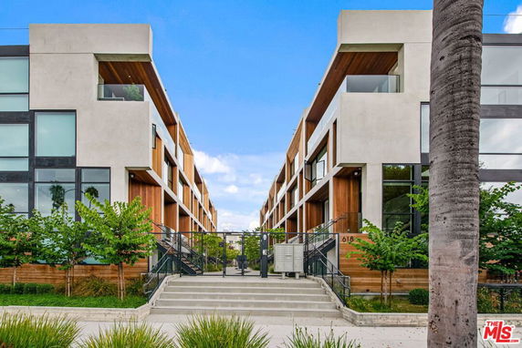 Front view of a modern multi-story building with large windows and wooden accents.