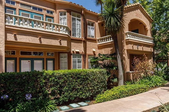 Front view of a two-story house with a balcony and arched entrance.