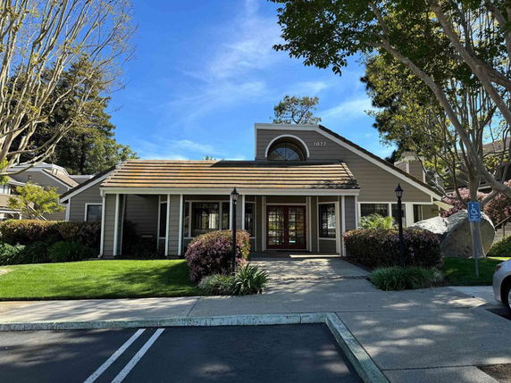 Front view of a single-story house with a sloped roof and visible front porch entrance.