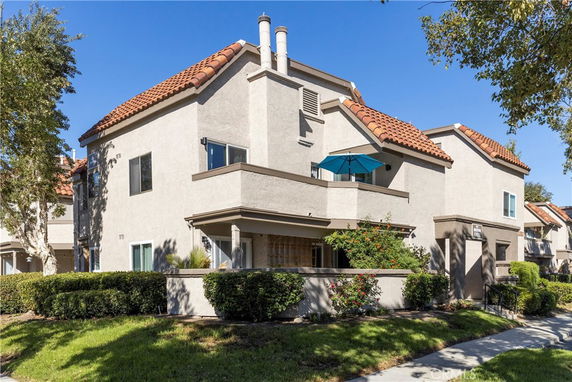 Front view of a multi-story house with tiled roof and balcony.