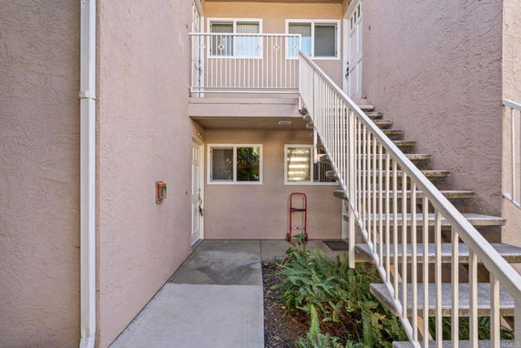 Outdoor entrance view with stairs and railing leading to upper level.