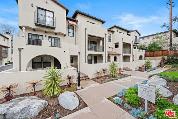 Front view of a multi-story residential building with balconies and arched entries.