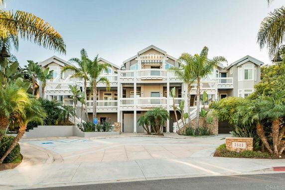 Front view of a multi-story residential building with balconies and palm trees.