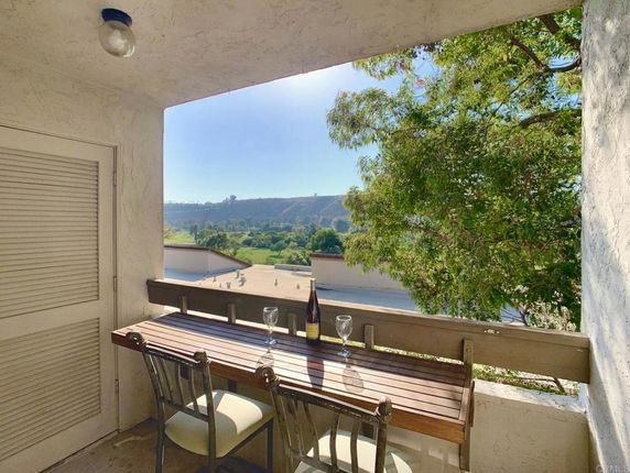 Balcony view of landscape with chairs and table.