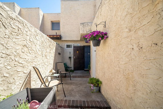 Front view of a house entrance with textured walls and hanging plants.