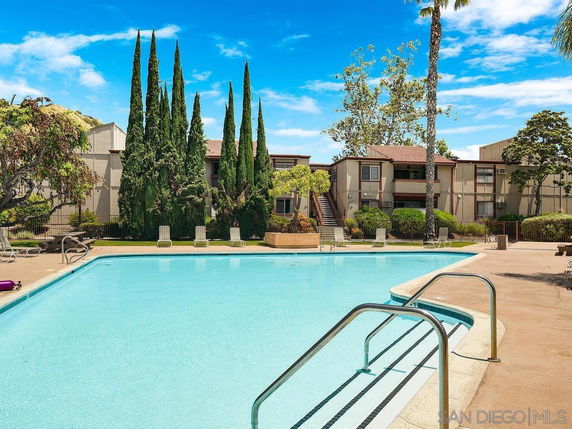 Outdoor swimming pool with surrounding buildings and trees.