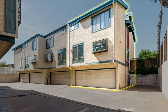 Front view of a multi-story apartment building with multiple garages on the ground level.