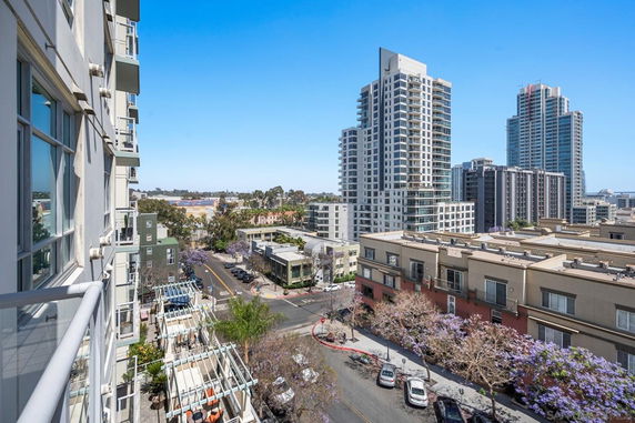 View of urban landscape from a balcony featuring tall buildings and streets.