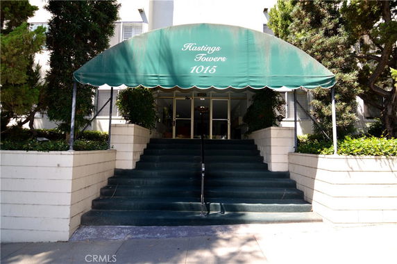 Front view of a building entrance with steps and a green canopy.
