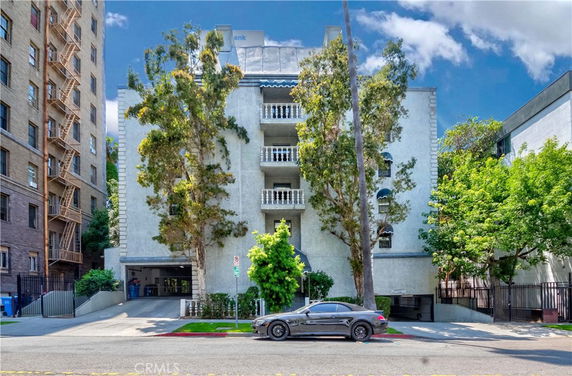 Front view of a multi-story residential building with balconies and a garage entrance.