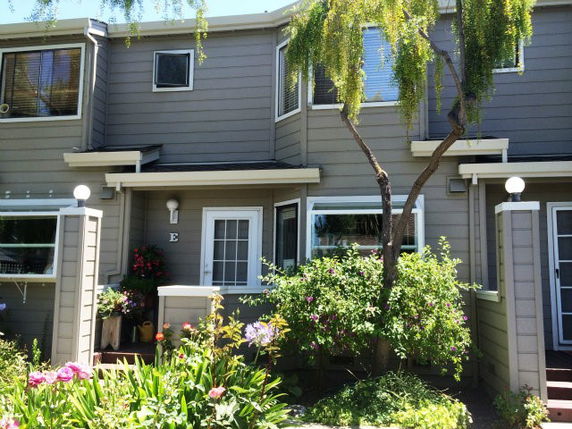 Front view of a two-story townhouse with a garden.