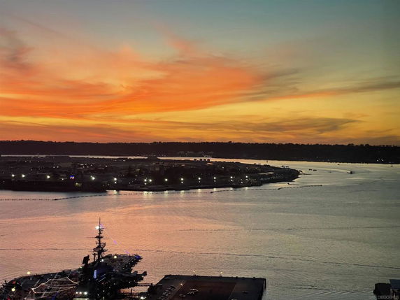 Panoramic view of a waterfront and distant skyline at sunset.
