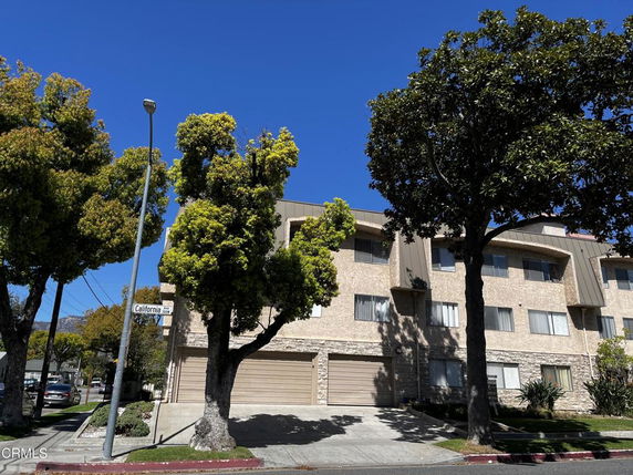 Front view of a multi-story residential building with multiple windows and garage doors.