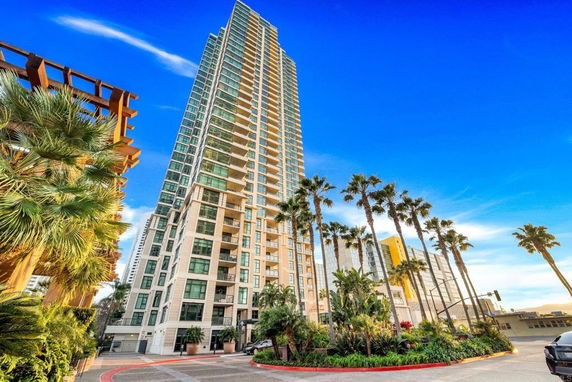 Front view of a tall residential building with numerous balconies.