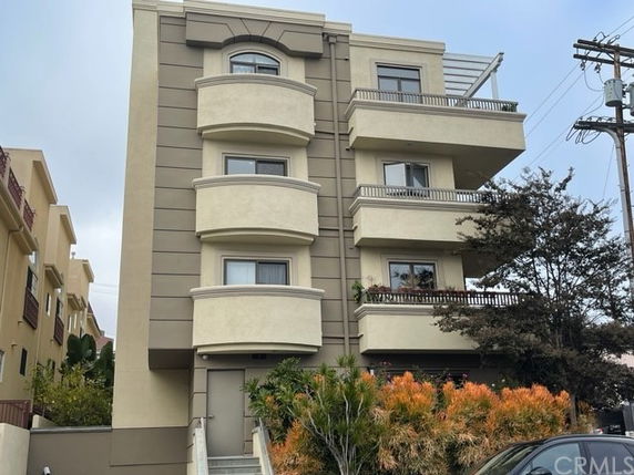 Front view of a multi-story residential building with balconies and entrance steps.