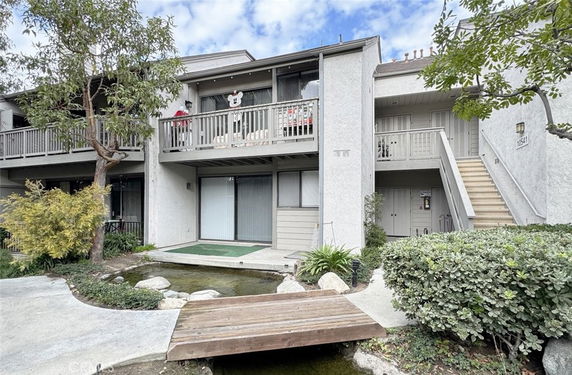 Front view of a multi-story residential building with balconies and stairs.