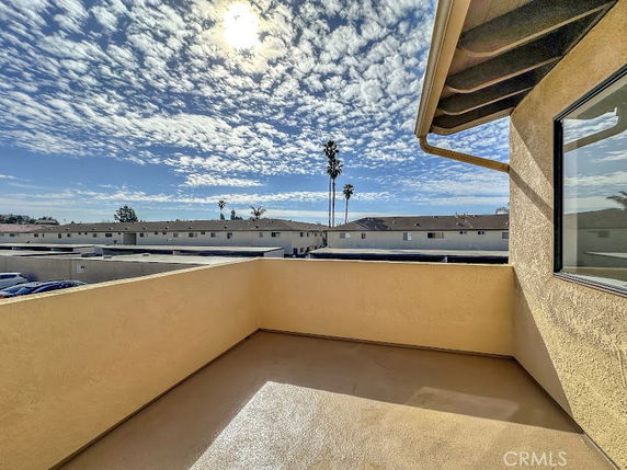 Wide angle view from a building looking towards other houses and a partly cloudy sky.