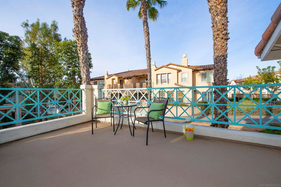 A balcony view overlooking neighboring houses and palm trees.