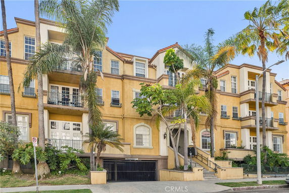 Front view of a multi-story residential building with balconies and an entrance.