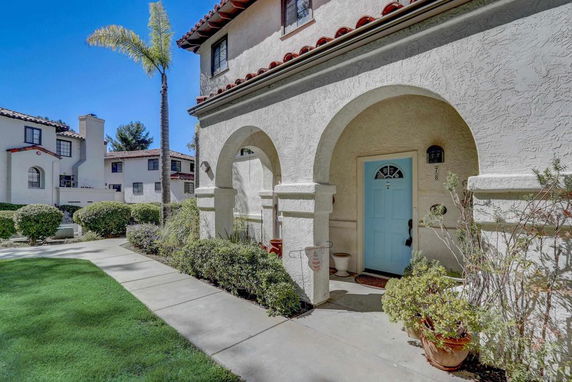 Front view of a two-story house with arched entrance and blue front door.