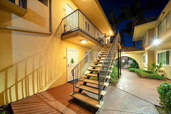 Exterior view of a two-story apartment building with stairs leading to the upper floor.