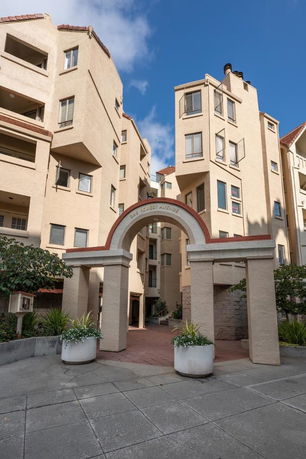Front view of a multi-story beige building with an archway entrance.